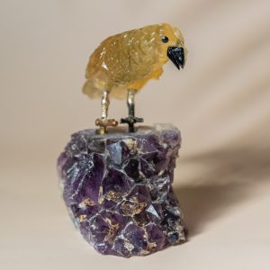 Handcrafted semi precious stone bird sculpture perched on natural amethyst geode