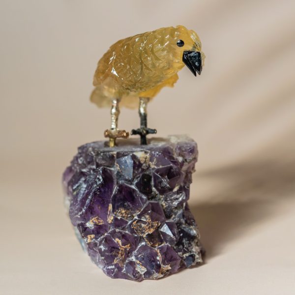 Handcrafted semi precious stone bird sculpture perched on natural amethyst geode