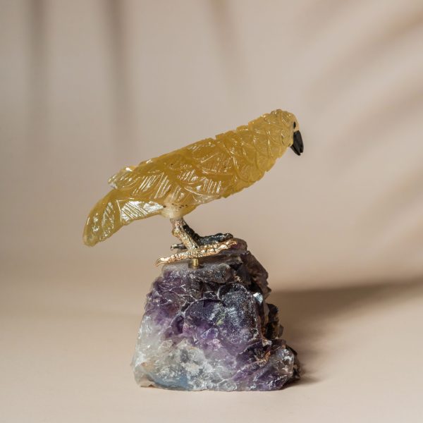 Back view of handcrafted stone bird sculpture with amethyst crystal base