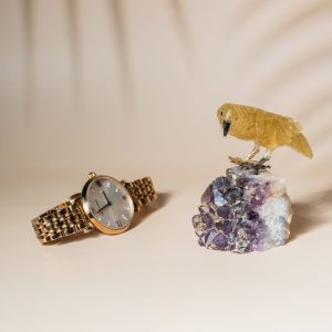 Stone bird sculpture on amethyst geode shown with wrist watch for size reference