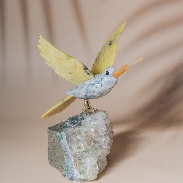 Hummingbird figurine in blue green sodalite with yellow wings on natural amethyst geode for home decor and gifting