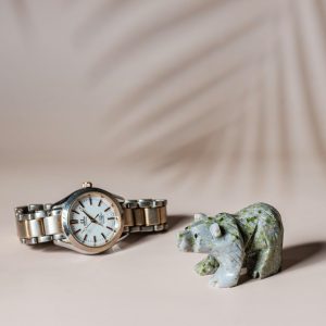 Light green jade bear sculpture shown with watch for size reference