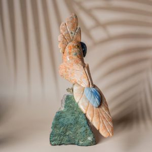Handcrafted orange calcite parrot figurine on amethyst geode