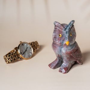 Purple jasper owl figurine shown with watch for size reference