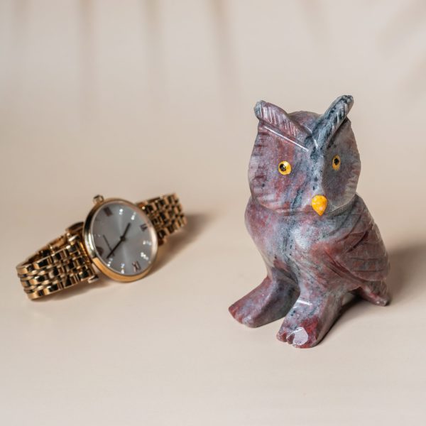 Purple jasper owl figurine shown with watch for size reference